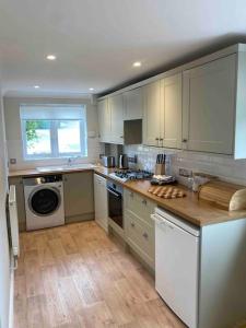 a kitchen with white cabinets and a stove top oven at Cotswold Cottage in Cheltenham