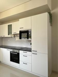 eine Küche mit weißen Schränken und schwarzen Arbeitsplatten in der Unterkunft Escape Villa in As Sīfah