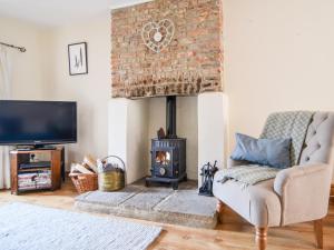 a living room with a fireplace and a couch and a tv at Heron Cottage in Colyton