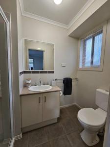 a white bathroom with a toilet and a sink at Beach Haven in Rosebud +13 photos