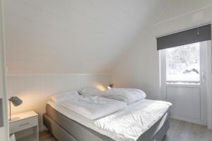 a white bed in a room with a window at Nærøysund Rorbuer AS in Rørvik