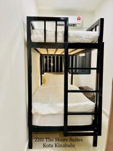 a black bunk bed with white sheets on it at ZHI The Shore Suites Kota Kinabalu in Kota Kinabalu