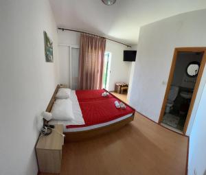 een slaapkamer met een bed met een rode deken bij Rooms with shared kitchen "Milica" in Drvenik