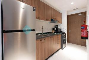 a stainless steel refrigerator in a kitchen with wooden cabinets at Lavish Pool View Apartment in Abu Dhabi
