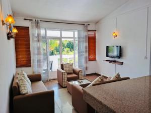 a living room with a couch and a tv at Cosy Two Bedroom Apartment in Grand Gaube
