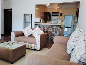 a living room with two couches and a kitchen at Cosy Two Bedroom Apartment in Grand Gaube