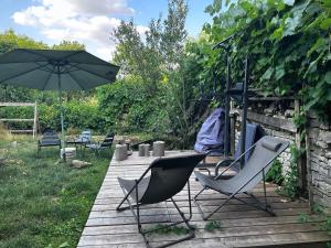 einen Tisch, Stühle und einen Regenschirm auf einer Holzterrasse in der Unterkunft Maison au bord de l’eau in Annay-sur-Serein