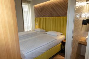 sypialnia z dużym łóżkiem z żółtym zagłówkiem w obiekcie City Hotel Pilvax w Budapeszcie