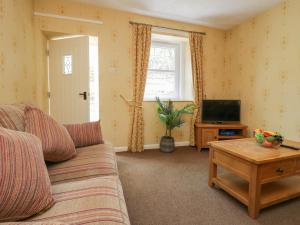 a living room with a couch and a tv at Garden Cottage No 2 in Keswick