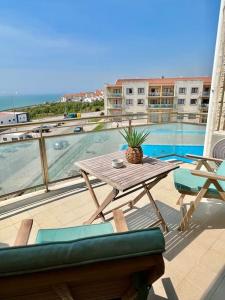 stół i krzesła na balkonie z basenem w obiekcie Ribeira DIlhas Beach Apartment w mieście Ericeira