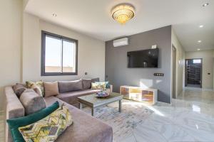 uma sala de estar com um sofá e uma mesa em Villa Vista , Piscine 22m , Jeux jardins , Terrain squash em Marraquexe