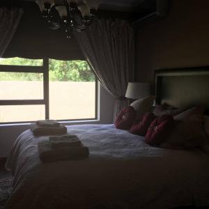 een slaapkamer met een bed met kussens en een raam bij Spacious home on a golf estate in Brits