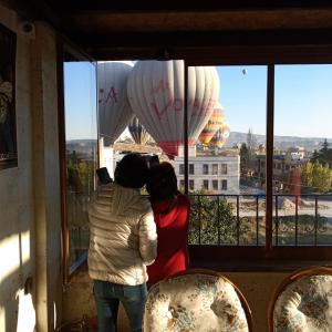 dwoje ludzi patrzących przez okno na balony w obiekcie Sun Rise View Hotel w Göreme