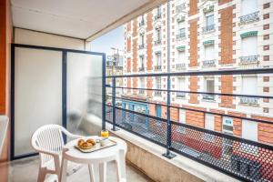 einen Tisch und einen Stuhl auf einem Balkon mit Blick auf ein Gebäude in der Unterkunft Zenitude Hôtel-Résidences Le Havre in Le Havre