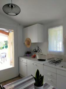 Una cocina con gabinetes blancos y una ventana. en Ô fil du THYM, en Sillans-la Cascade