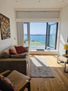 a living room with a couch and a large window at Sea View Apartment at One Lusty Glaze in Newquay