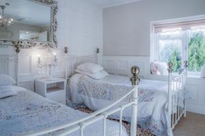 a white bedroom with two beds and a mirror at Angel Cottage - 3 Bedroom Cottage - Stepaside in Stepaside