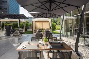 an outdoor patio with tables and umbrellas at Falkensteiner Hotel Belgrade in Belgrade