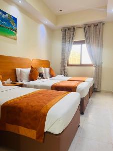 um quarto de hotel com três camas e uma janela em Marhaba Deira Hotel em Dubai