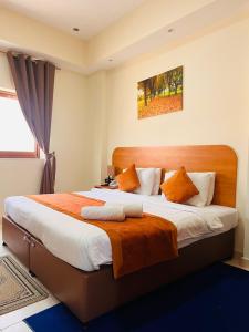 um quarto com uma cama grande com almofadas laranja e branca em Marhaba Deira Hotel em Dubai