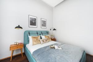 a bedroom with a blue bed with a book on it at Cracovian House - LoftAffair in Kraków