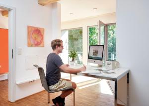 Penthouse one في Wilnsdorf: رجل يجلس في مكتب وبه جهاز كمبيوتر