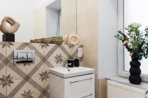 baño con lavabo y jarrón con flores en Cracovian House by LoftAffair, en Cracovia