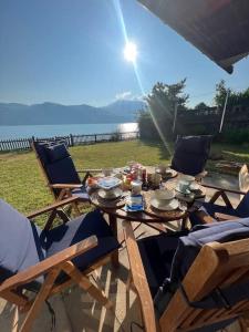 een houten tafel met stoelen en een tafel met eten erop bij NEB-THUN Seehaus Einigen in Einigen