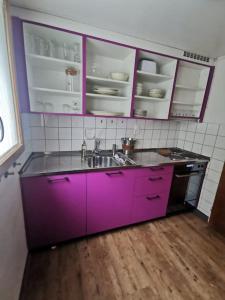- une cuisine avec des placards violets et un évier dans l'établissement NEB-THUN Seehaus Einigen, à Einigen