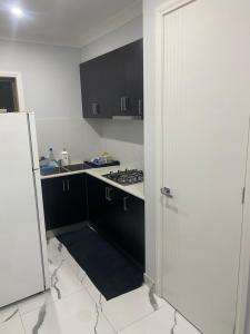 een keuken met zwarte kasten en een witte koelkast bij Private room in shared house in Wollert