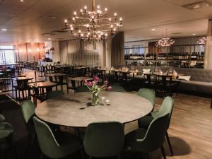 una sala da pranzo con tavoli, sedie e lampadario a braccio di Vann Spa Hotell & Konferens a Brastad