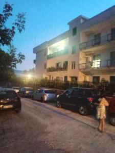 a woman standing in front of a building with parked cars at I Rifugi di Noah Santa Maria a Vico- in Santa Maria a Vico