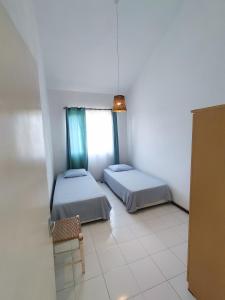 Zimmer mit 2 Betten, einem Stuhl und einem Fenster in der Unterkunft BEACH APARTMENT PEREYBERE in Pereybere
