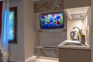 a kitchen with a sink and a tv on a wall at Moustheni Blue Guest House in Mousthéni