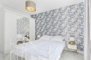 Habitación blanca con papel pintado de flores azul y blanco en Lumina luxury apartments Manufactura, en Łódź