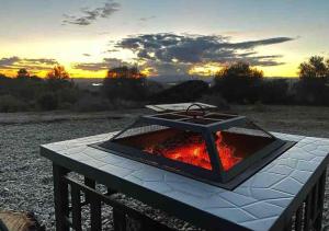 uma fogueira sobre uma mesa com um pôr-do-sol ao fundo em Unique Stay - Tiny Eco Country Cottage em Cabanes