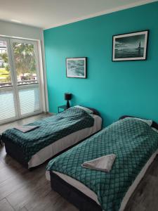 two beds in a room with blue walls at Apartamenty Bulwar Nadmorski, Rowy in Rowy