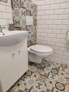 a bathroom with a toilet and a sink and tiles at Apartamenty Bulwar Nadmorski, Rowy in Rowy