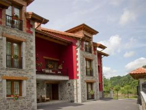 een rood gebouw met bloemen op de balkons bij Apartamentos Rurales La Viña in Cangas de Onís