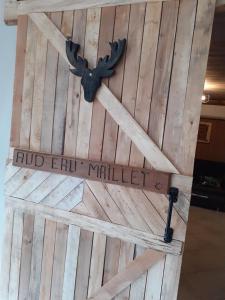 een houten schuurdeur met een bord erop bij aud eau maillet in Tilques