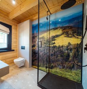 a bathroom with a shower with a painting on the wall at Osada Miód Malina in Istebna