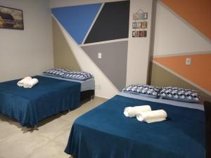 two beds in a room with blue sheets and white pillows at Sophia I - Praia Grande in Arraial do Cabo