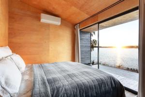 Schlafzimmer mit einem Bett und Blick auf das Wasser in der Unterkunft World's End - 2 Luxury Beachfront Villas (425m2) in Mikkeli