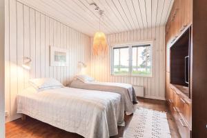 1 dormitorio con 2 camas y TV. en World's End - 2 Luxury Beachfront Villas (425m2) en Mikkeli
