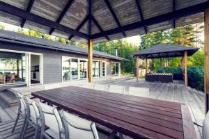 a large wooden table and chairs on a deck at World's End - 2 Luxury Beachfront Villas (425m2) in Mikkeli