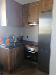 a kitchen with wooden cabinets and a stainless steel refrigerator at Casa vistas inmejorables in Caserío Carraspite