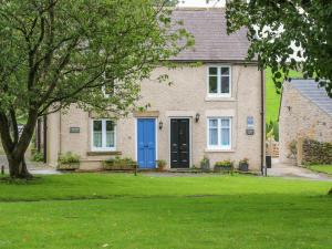 a house with a blue door and a yard at Candlelight Cottage in Buxton