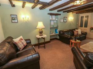 a living room with two leather couches and a lamp at Candlelight Cottage in Buxton