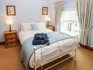 a bedroom with a bed with a blue blanket on it at Candlelight Cottage in Buxton