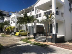 a yellow car parked in front of a white building at Spacious Three Bedroom Apartment in Grand Gaube